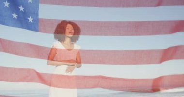 Amerikan bayrağı, sahile atlayan Afrikalı Amerikalı bir kadına doğru dalgalanıyor. Amerika 'nın bağımsızlığı vatansever tatil konsepti