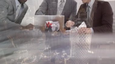 İş adamlarının arka plandaki şehir manzarasına karşı ofiste dizüstü bilgisayarla tartıştıkları kısım. küresel iş ve teknoloji kavramı