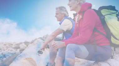 Hızlı hareket eden bulutların üzerinde dağlarda yürüyüş yapan Kafkasyalı mutlu çift. etkin emeklilik yaşam tarzı konsepti dijital olarak oluşturulmuş video.