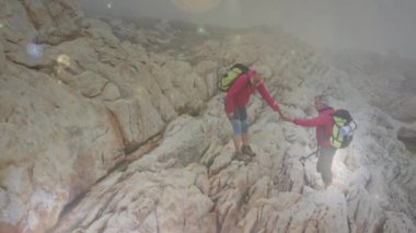 Kafkasyalı üst sınıf çifti kayalıklarda el ele tutuşurken, Bokeh ışıklı noktalarından düşerken. aktif yaşam tarzı, doğa, sağlıklı emeklilik ve özgürlük konsepti, dijital olarak oluşturulmuş video.