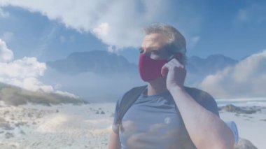 Kafkas kıdemli adam kıyı boyunca hızlı hareket eden bulutların üzerinde yürüyüş yapıyor. Coronavirus covide 19 pandemik konsept dijital olarak oluşturulmuş video sırasında aktif emeklilik yaşam tarzı.