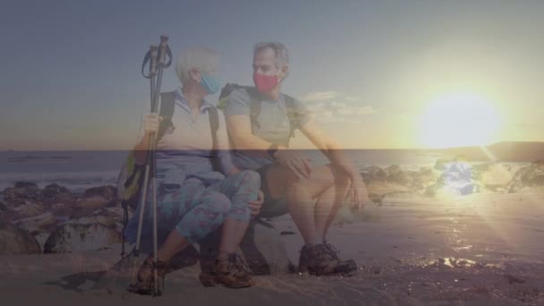 白种人的老两口戴着面具在海岸上远足休息 日落时飞越大海 Coronavirus大流行病概念期间的健康退休和自由 数码视频 — 图库视频影像