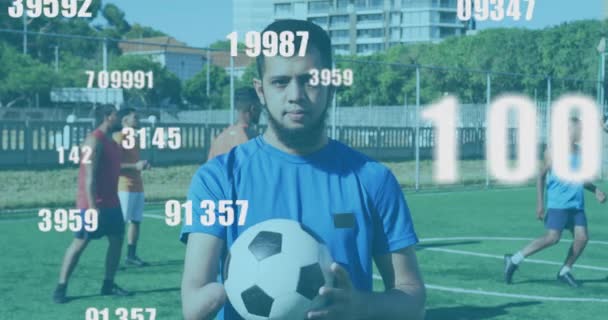 Wiele Zmieniających Się Liczb Przeciwko Portretowi Męskiego Piłkarza Trzymającego Piłkę — Wideo stockowe