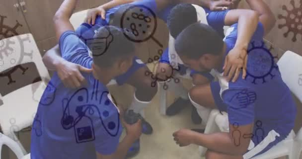 ロッカールームでハドルを形成する男性サッカー選手のチームに対するコロナウイルスの概念アイコン スポーツとCovid 19パンデミックの概念 — ストック動画