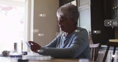 Sosyal medya simgelerinin animasyonu ve akıllı telefon kullanan yaşlı kadın üzerindeki afişler. küresel ağ, sosyal medya, teknoloji ve dijital arayüz kavramı dijital olarak oluşturulmuş video.