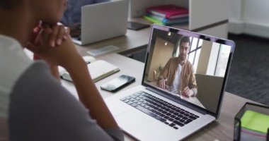 Afrika kökenli Amerikalı bir kadın, ofiste erkek meslektaşıyla dizüstü bilgisayarda video konferansı yapıyor. iş, profesyonellik ve teknoloji kavramı
