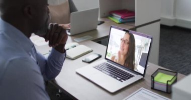 Afrika kökenli Amerikalı son sınıf öğrencisi, ofisteki bayan meslektaşıyla laptopta görüntülü görüşme yapıyor. iş, profesyonellik ve teknoloji kavramı