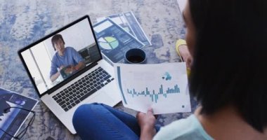 Afro-Amerikalı bir kadın elinde bir belge tutuyordu ve evdeki bilgisayarından bir video görüşmesi yapıyordu. ev kavramından çalışmak