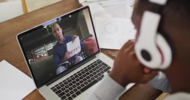 Kulaklık takan Afro-Amerikan erkek üniversite öğrencisi laptopuyla evde video görüşmesi yapıyor. uzak öğrenim çevrimiçi eğitim kavramı