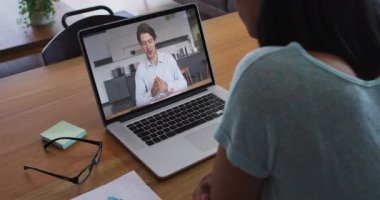 Afrikalı Amerikalı bir kadın, erkek iş arkadaşıyla evdeki bilgisayarında video görüşmesi yapıyor. ev kavramından çalışmak