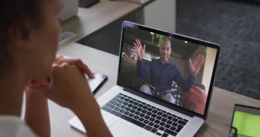 Afrika kökenli Amerikalı bir kadın, erkek meslektaşı ile bilgisayarında video görüşmesi yapıyor. iş, profesyonellik ve ofis kavramı