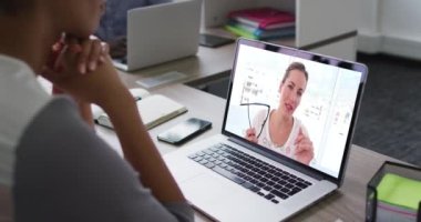 Afrika kökenli Amerikalı bir kadın, ofis arkadaşı olan bir bayanla dizüstü bilgisayarda video konferansı yapıyor. iş, profesyonellik ve teknoloji kavramı