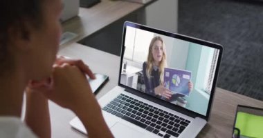 Afrika kökenli Amerikalı bir kadın, ofis arkadaşı olan bir bayanla dizüstü bilgisayarda video konferansı yapıyor. iş, profesyonellik ve teknoloji kavramı
