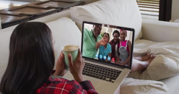 一个拿着咖啡杯的非洲裔美国女人坐在家里的沙发上 在笔记本电脑上有一个视频通话 在隔离隔离状态下待在家里 — 图库视频影像