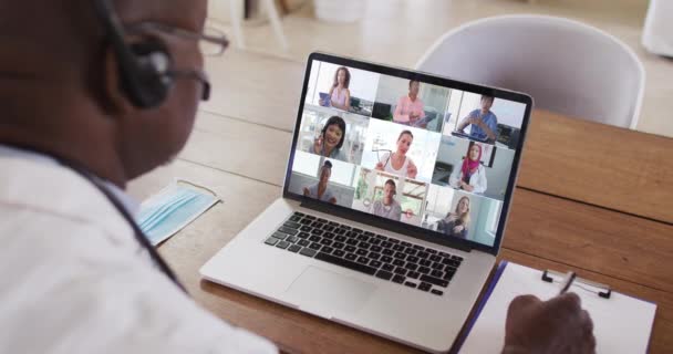 Médico Afro Americano Toma Notas Enquanto Faz Uma Videoconferência Portátil — Vídeo de Stock