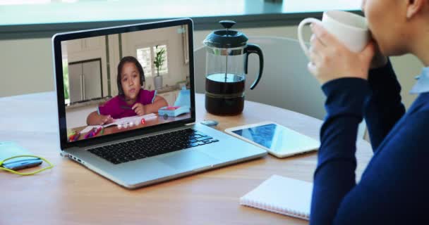 白人女性教師は自宅でノートパソコンでビデオ通話をしながらコーヒーを飲み メモを取る 距離学習オンライン教育の概念 — ストック動画