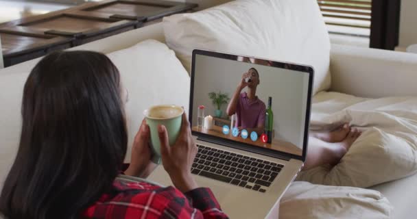 Африканская Американка Держит Кофейную Чашку Видеозвонком Ноутбуке Сидя Дома Диване — стоковое видео