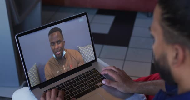 アフリカ系アメリカ人男性は自宅のノートパソコンで男性のオフィスの同僚とビデオ通話をしています 家庭の概念から — ストック動画