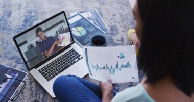 Bir belgeyi elinde tutan Afrikalı Amerikalı bir kadın dizüstü bilgisayarında bayan meslektaşıyla görüntülü konuşma yapıyor. iş, profesyonellik ve teknoloji kavramı