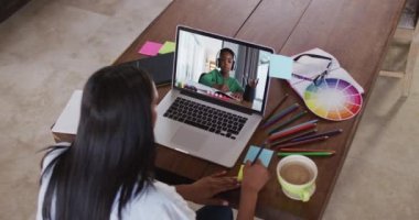 Bilgisayarında bir çocukla video görüşmesi yaparken notlara yazı yazan Afro-Amerikan bayan öğretmen. uzak öğrenim ve çevrimiçi eğitim kavramı