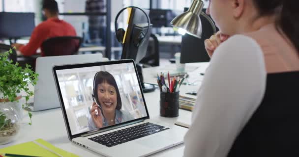 白种人女商人坐在办公桌前 用笔记本电脑与女同事进行视频通话 在现代化的办公室工作 — 图库视频影像