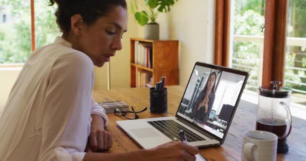 アフリカ系アメリカ人の女性は 自宅のノートパソコンでビデオ通話をしている間にメモを取る 家庭の概念から — ストック動画