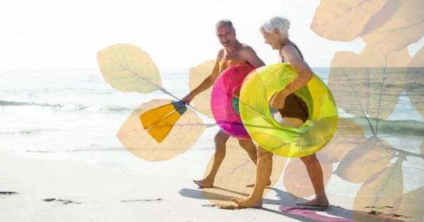 Composition Happy Senior Couple Holding Inflatables Smiling Beach Autumn Foliage — Stock Photo, Image