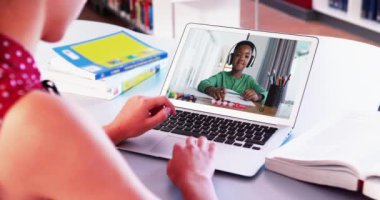 Beyaz kız evde Afro-Amerikan bir çocukla video görüşmesi yaparken dizüstü bilgisayar kullanıyor. uzak öğrenim ve çevrimiçi eğitim kavramı