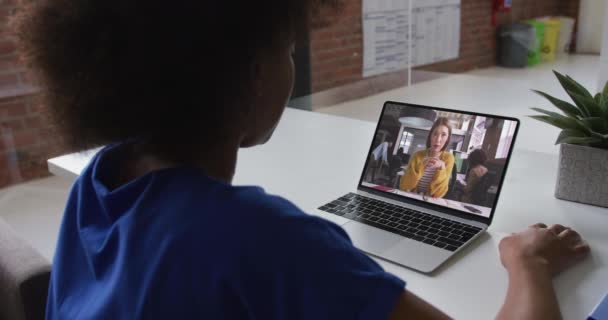 アフリカ系アメリカ人のビジネスマンは 女性の同僚とビデオ通話をするラップトップを使用してデスクに座っています オンライン会議隔離中の隔離作業 — ストック動画