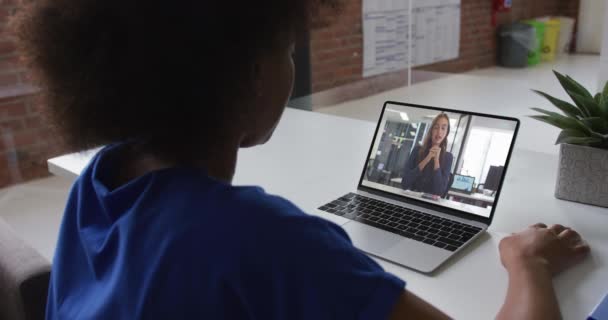 アフリカ系アメリカ人のビジネスマンは 女性の同僚とビデオ通話をするラップトップを使用してデスクに座っています オンライン会議隔離中の隔離作業 — ストック動画