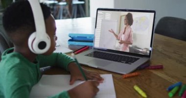 Evde dizüstü bilgisayarında kadın öğretmenle video görüşmesi yapan Afrikalı Amerikalı çocuk. uzak öğrenim ve çevrimiçi eğitim kavramı