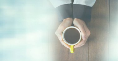 Ahşap yüzeyde, üzerinde fotokopi alanı olan sarı kahve fincanı tutan kadın kompozisyonu. içki ve kafein konsepti dijital olarak oluşturulmuş görüntü.