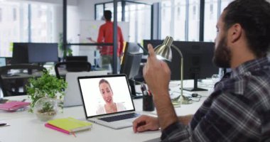Orta Doğulu bir adam, iş yerinde dizüstü bilgisayarında iş arkadaşıyla görüntülü görüşme yapıyor. iş, uzaktan çalışma ve teknoloji kavramı
