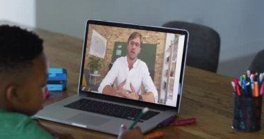 Evde dizüstü bilgisayarında erkek öğretmenle video görüşmesi yapan Afrikalı Amerikalı çocuk. uzak öğrenim ve çevrimiçi eğitim kavramı