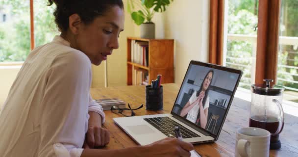 Mujer Afroamericana Tomando Notas Mientras Recibe Videollamadas Con Una Colega — Vídeos de Stock