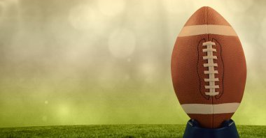 Sahnede rugby topu kompozisyonu, fotokopi alanı ve sarı arka planda ışık lekeleri. spor ve yarışma konsepti dijital olarak oluşturulmuş görüntü.