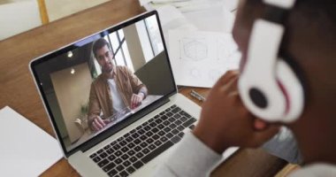 Afrika kökenli Amerikalı iş adamı dizüstü bilgisayarını kullanarak erkek meslektaşıyla görüntülü konuşma yapıyor. Çevrimiçi toplantı, karantina süresince tecrit altında çalışma.