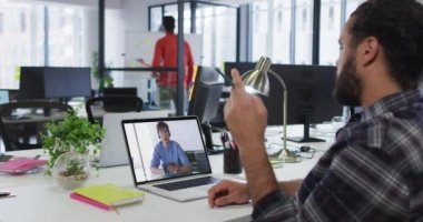 Orta Doğulu bir adam, erkek meslektaşıyla ofiste video görüşmesi yapıyor. iş, profesyonellik ve teknoloji kavramı