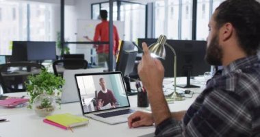 Orta Doğulu bir adam, erkek meslektaşıyla ofiste video görüşmesi yapıyor. iş, profesyonellik ve ofis kavramı