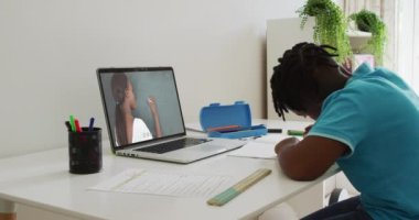 Evde dizüstü bilgisayarında kadın öğretmenle video görüşmesi yapan Afrikalı Amerikalı çocuk. uzak öğrenim ve çevrimiçi eğitim kavramı