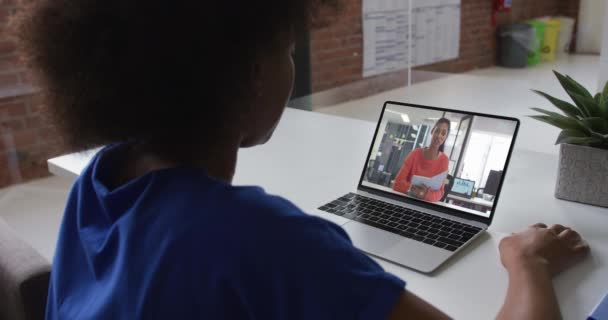 アフリカ系アメリカ人女性のバックビューオフィスでラップトップで女性同僚とビデオ通話をしています ビジネス リモートワーク テクノロジーの概念は — ストック動画
