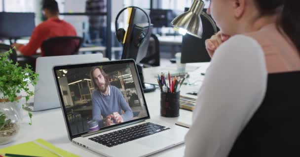 オフィスの男性同僚とノートパソコンでビデオ通話をしている白人女性 ビジネス プロ意識 テクノロジーの概念 — ストック動画