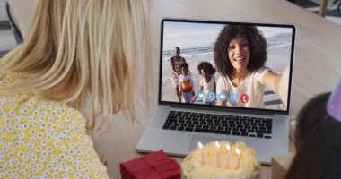 Kafkas anne ve kızı laptoplarını kullanarak masada oturuyorlar ve doğum günü videosu izliyorlar. Karantina süresince evde tecrit altında..