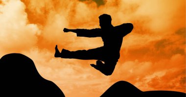 Turuncu gökyüzü üzerinde güneş batarken erkek dövüş sanatçısının silueti. spor ve yarışma konsepti dijital olarak oluşturulmuş görüntü.