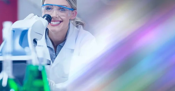 Composition of smiling female lab technician using microscope, with blurred copy space to right. medical and science research concept digitally generated image.