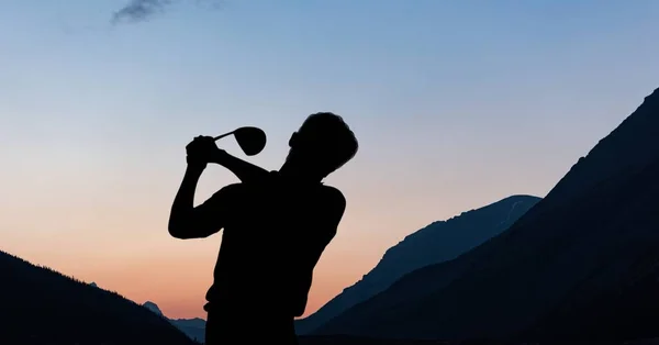 Composition of silhouette of male golf player over landscape and blue sky with copy space. sport and competition concept digitally generated image.