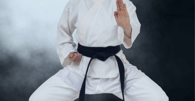 Duman bulutlarının üzerinde siyah kuşak taşıyan erkek dövüş sanatçısının göbek yapısı. Spor ve rekabet konsepti dijital olarak oluşturulmuş imaj.