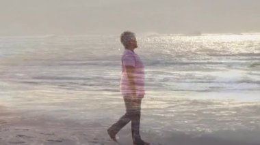 Deniz kenarında yürüyen mutlu yaşlı kadının üzerinde parlayan ışığın animasyonu. emeklilik ve yaşlı yaşam konsepti dijital olarak oluşturulmuş video.