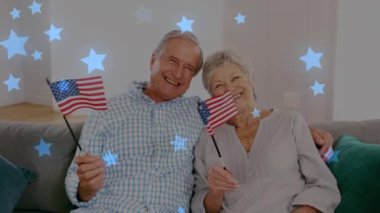 Amerikan bayrakları tutan mutlu yaşlı çiftin portresinin üzerinde parlayan mavi yıldızların animasyonu. emeklilik ve yaşlı yaşam konsepti dijital olarak oluşturulmuş video.