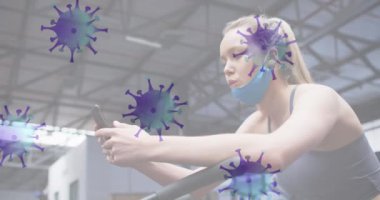 Spor salonunda akıllı telefon kullanan beyaz bir kadına karşı hareket eden Covid-19 hücreleri işaretini durdurun. Coronavirus covid-19 salgın konsepti
